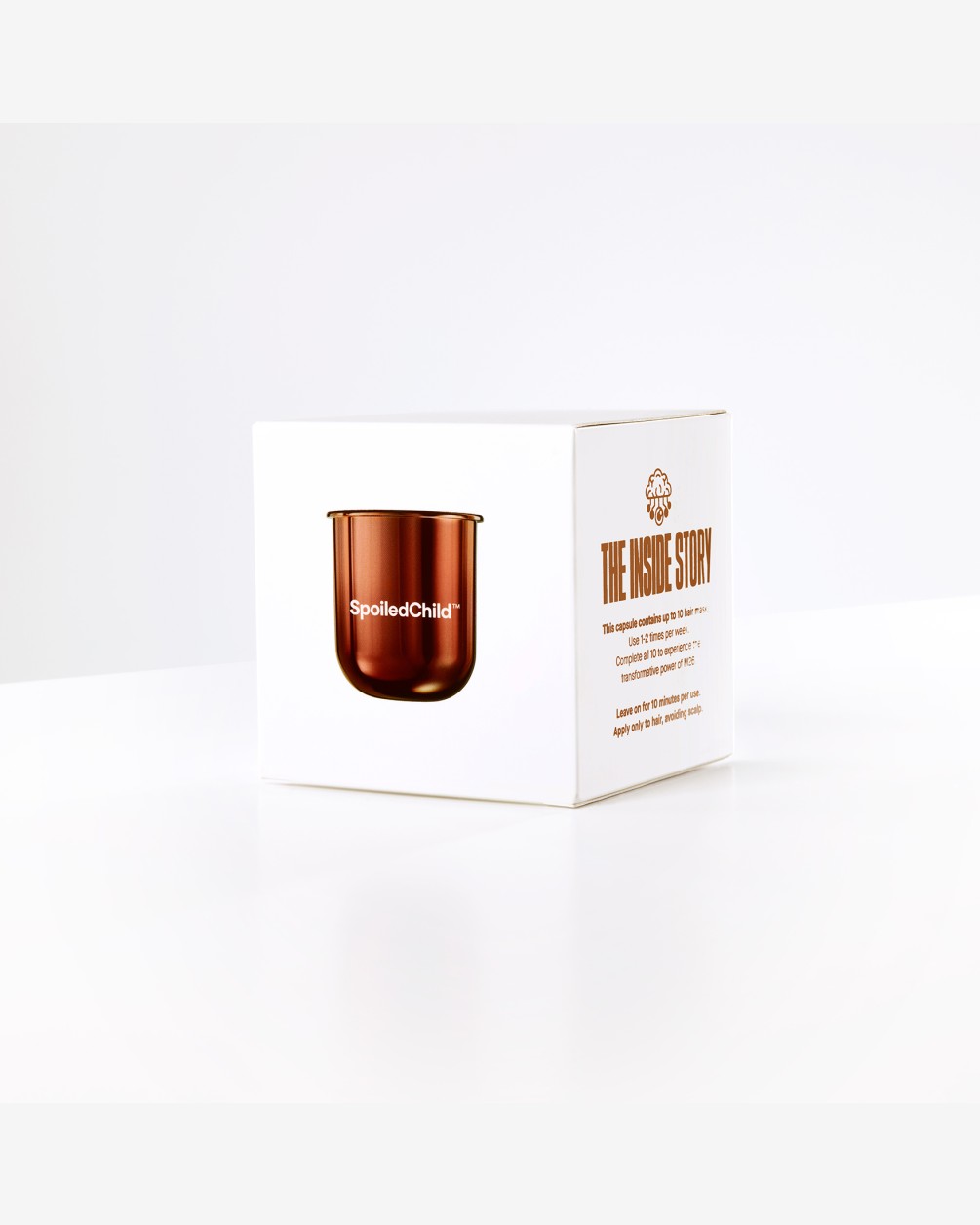 A white square product box for SpoiledChild featuring an image of the metallic copper refill M26 capsule on the front. The side of the box includes text detailing the brand's sustainability mission.
